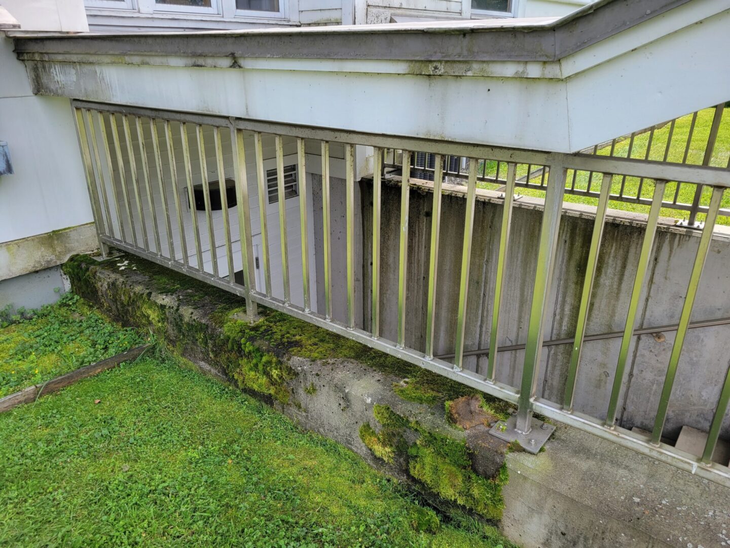 A balcony with moss growing on it and concrete steps.