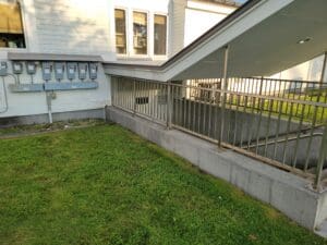A house with grass and metal railing.