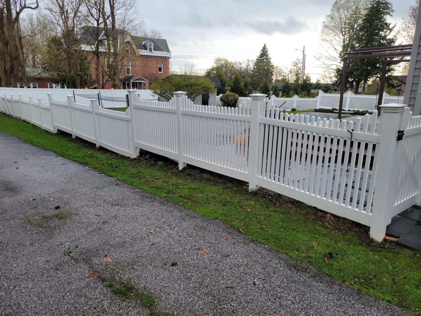 A white fence is shown on the side of a road.