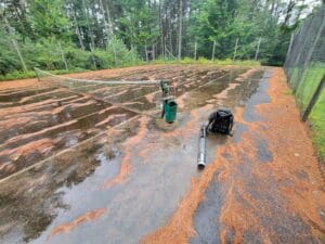 A person standing in the mud near some trees.