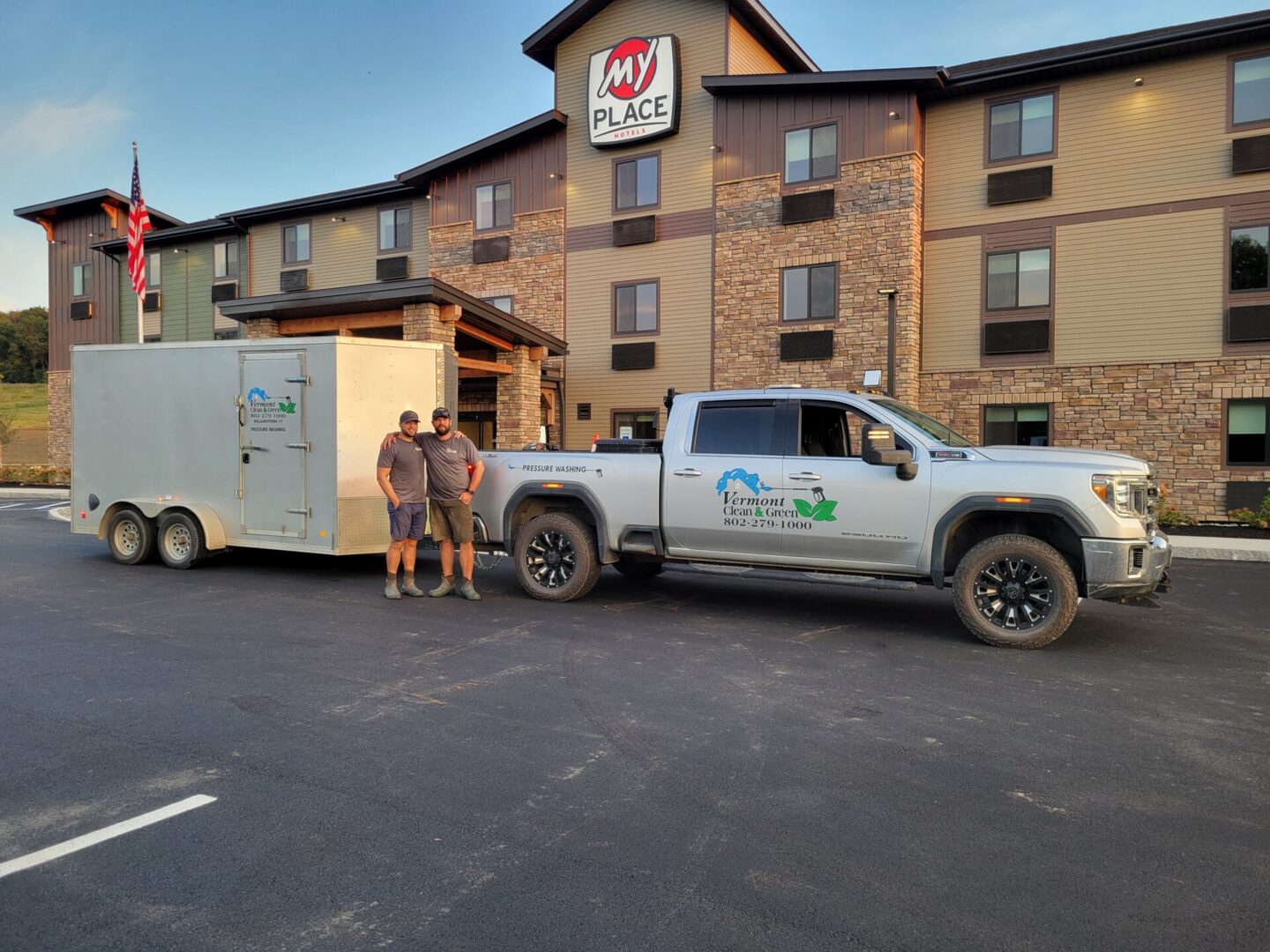 Two men standing next to a truck and trailer.